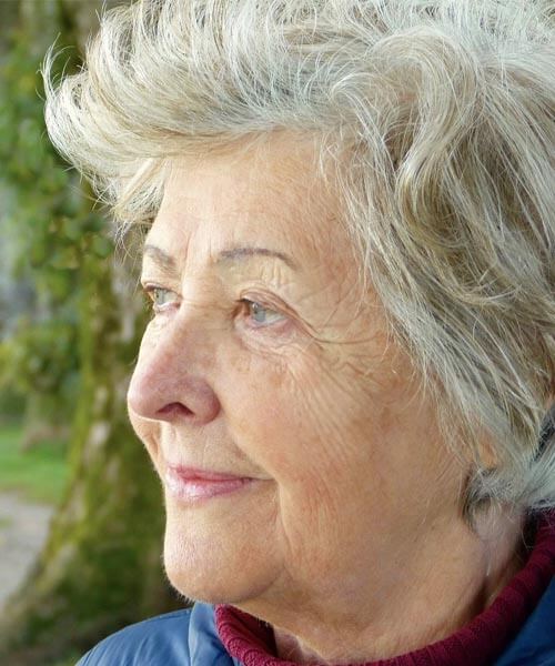 Slika se uporablja za članek oziroma blog CBD in epilepsija. Na sliki je starejša gospa, ki gleda v daljavo.