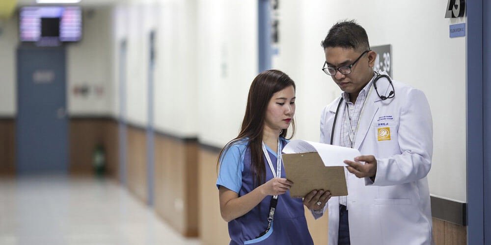 Na sliki sta prikazana doktor in medicinska sestra, ki skupaj si ogledujeta kartoteko od stranke. Blog Demenca